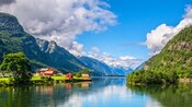 A fjord surrounded by towering mountains with a scattering of houses along the shoreline