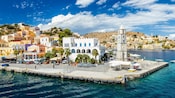 The harbor town of Rhodes, Greece, with buildings, a clock tower and boats along the pier