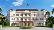 Hotel con arquitectura de estilo colonial con ventanas arqueadas, un asta central y las palabras “Raffles Hotel” 