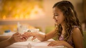 Una niña sonríe mientras le hacen una manicura.