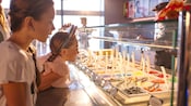 Two young girls eagerly browsing an ice cream bar at Edna À La Mode Sweets