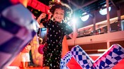 A smiling child jumps in a bouncy house inside a gymnasium