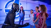 Black Panther agasaja a un grupo de niños pequeños en un elegante entorno de sede central