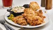 A fried chicken dinner platter with mashed potatoes and a biscuit