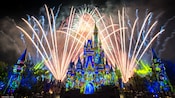 Fireworks burst over Cinderella Castle as lights cover it in a stained glass theme