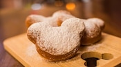 Three Mickey-shaped beignets covered in sugar
