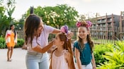 A woman puts a Minnie Mouse headband on her daughter