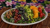 A kale and cabbage salad, with walnuts, grapes, blueberries, edamame, mandarin oranges and tomatoes
