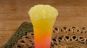 A large cup of Mango Passion Fruit Shaved Ice rests on a placemat