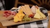 A charcuterie platter featuring sliced meats, crackers, cheese and pickles
