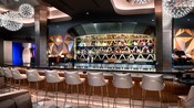 A bar and stools in front of liquor lined shelves at Geo 82 at Epcot