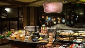 A cash register on a counter next to pastries, bottled sodas and an assortment of other snacks