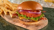 A cheeseburger with onion, tomato, lettuce and bacon, served with French fries