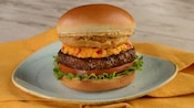 A burger topped with tomatoes, pimento cheese and bacon