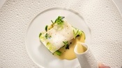 Um prato elegante com uma peça de peixe ornamentada com folhinhas verdes
