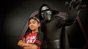 A young girl standing with her arms crossed next to Kylo Ren making a dramatic pose
