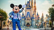 Mickey Mouse, parado junto al Cinderella Castle en el Parque Temático Magic Kingdom, saluda a la cámara