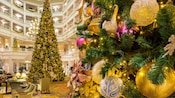 Un gran lobby de hotel decorado para las fiestas con árboles de Navidad y guirnaldas