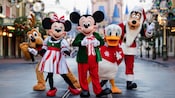 Mickey Mouse and Friends wearing Christmas outfits while standing in the middle of Main Street, USA