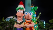 Phineas and Ferb wearing Christmas hats and scarves while Perry the Platypus emerges from the top of a Christmas tree behind them