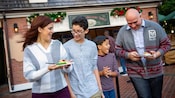 A mom, a dad and their 2 sons share small plates filled with tempting sweets and fruity holiday treats
