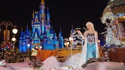 Elsa standing in a snowy landscape in front of Cinderella Castle