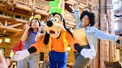 2 women posing for a photo with Goofy in the lobby of Disney's Wilderness Lodge