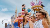 A family of 4 watching a parade in Magic Kingdom park