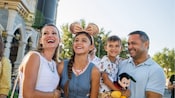 Parents and their 2 kids smile near Cinderella Castle