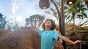 Un enfant regardant vers le haut alors que l’eau tombe d’une fontaine à proximité au Journey of Water, inspiré par Moana
