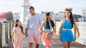 Una pareja y sus 2 hijas en un muelle junto a Disney’s Yacht Club Resort y Disney’s Beach Club Resort