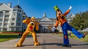 Goofy e Pluto posando para uma foto em uma passarela que leva ao Disney’s Yacht Club Resort