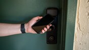 A person holds a smartphone up to a hotel room door handle at Disney’s Coronado Springs Resort