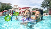A mother and daughter swimming in a pool at Disney's BoardWalk Inn