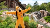Pluto standing with his arms open in front of Disney's Wilderness Lodge