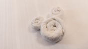 A towel folded into the shape of Mickey Mouse ears on a bed