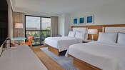 Una habitación de hotel con 2 camas Queen Size, un tocador, una mesa con silla y un balcón en Walt Disney World Swan