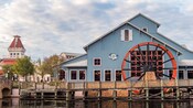 Disney’s Port Orleans Resort Riverside, a farm style building with a large water wheel and a wooden bridge, by the banks of the Sassagoula River
