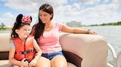 A mother and daughter seated on a motorized boat along Seven Seas Lagoon in Walt Disney World Resort