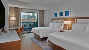 Una habitación de hotel con 2 camas dobles, una mesa con silla y un balcón en Walt Disney World Swan Hotel