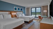 Una habitación de hotel con 2 camas Queen Size, un tocador y una mesa con silla en Walt Disney World Swan Hotel