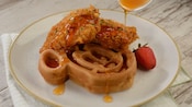 Un waffle en forma de cabeza de Mickey y 2 trozos de pechuga de pollo frita, rociados con miel de sriracha