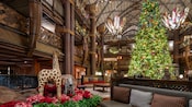 The grand lobby at Disney’s Animal Kingdom Lodge decorated for the holidays with poinsettias, garlands, lights and a giant Christmas tree