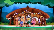 The cast of Bluey’s Best Day Ever pose on a stage set designed to look like a house in the woods
