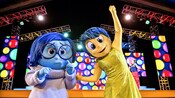 Tristeza y Alegría de “Inside Out” posando frente a un cantante en un escenario