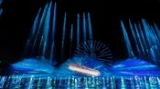 Una fuente de agua con luces y una rueda de la fortuna en el espectáculo World of Color One en Disneyland Resort