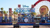 Un escenario con instrumentos musicales y las palabras “Disney California Adventure Food & Wine Festival”, con Pixar Pal A Round en el fondo