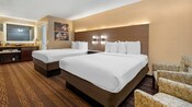 A Best Western Plus Stovall's Inn Standard Room with 2 beds, a nightstand, a sink, a mirror, a bathroom and 2 armchairs