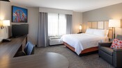La Suite Estudio con cama Queen Size en Candlewood Suites Anaheim Resort Area con una cama Queen Size, un sofá, una lámpara de pie, una mesa de noche, un televisor y un escritorio