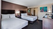 A king bed, a double bed and a nightstand in a bedroom with 2 paintings on the walls and a bureau